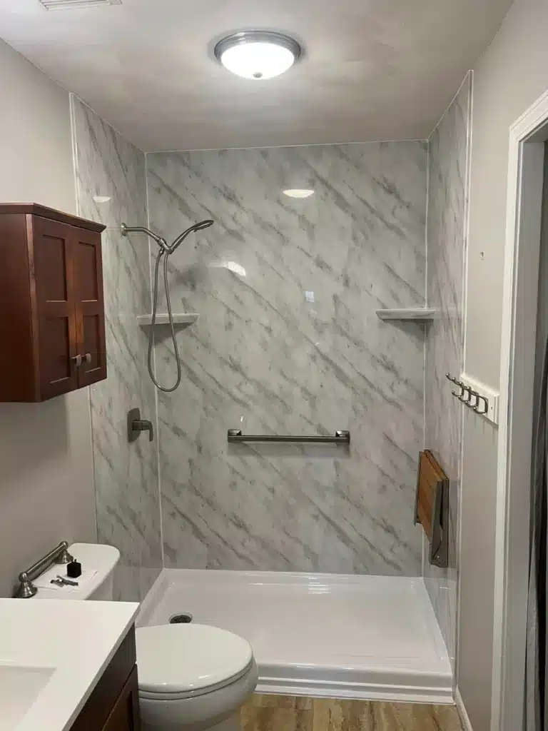 Walk-in shower with textured wall panels and grab bar in Dayton OH remodel.